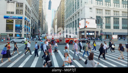 New York City, Circa 2017: FDNY fire department truck crossing busy Manhattan intersection during morning rush hour. Commuter people walk to work in M Stock Photo