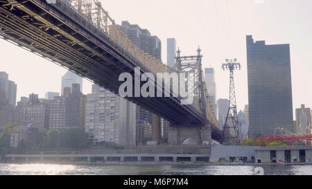 Wide establishing photo day time exterior of Queensboro bridge and tramway cable against Manhattan skyline background in late evening Stock Photo