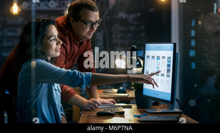 Beautiful Female Mobile Gaming Application Developer Talks With Her Male Colleague, They Discuss Creative Design. Stylishly Lit Office. Stock Photo