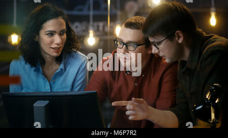 Three Office Employees Have Discussion about Ongoing Project, They Point at Personal Computer Screen. They Work in the Creative Office. Stock Photo
