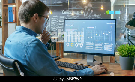 Financier Works on a Personal Computer Showing Statistics, Graphs and Charts. In the Background His Coworker and Creative Office. Stock Photo