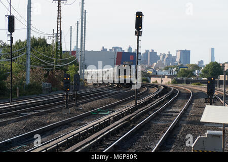 Generic commuter train traveling on track with New York City skyline in background during the evening rush hour commute Stock Photo