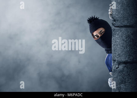 Robber hiding behind a empty wall with space for text Stock Photo