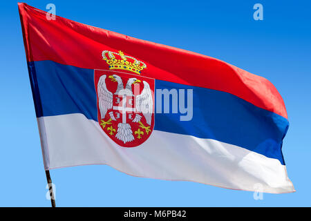 Official flag of republic of Serbia waving against blue cloudless sky Stock Photo