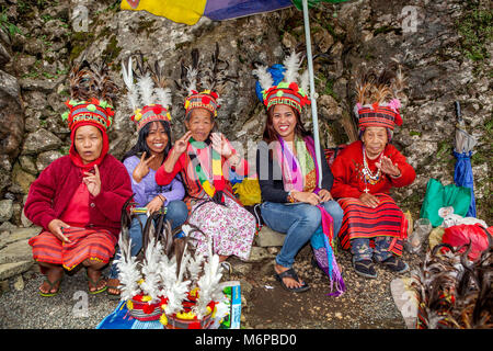 Tourists sit with three Ifugao tribal women dressed in native traditional costume at a tourist attraction in Baguio, Luzon, Philippines. Stock Photo