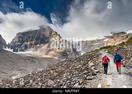 Hikers on Plain of the Six Glaciers Trail, scree-covered slopes, Mount Lefroy on left, Mount Victoria in clouds, Banff National Park, Alberta, Canada Stock Photo