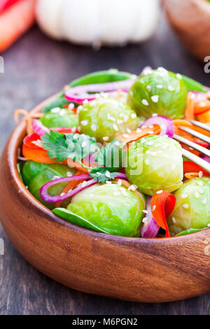 Portion  of Brussel Sprouts with carrot and onions on wooden table Stock Photo