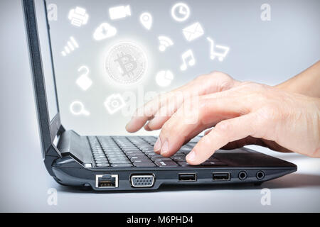 Hands typing on keyboard with Bitcoin in the center of common media icons. Concept of growing widespread use of digital virtual cryptocurrency payment Stock Photo