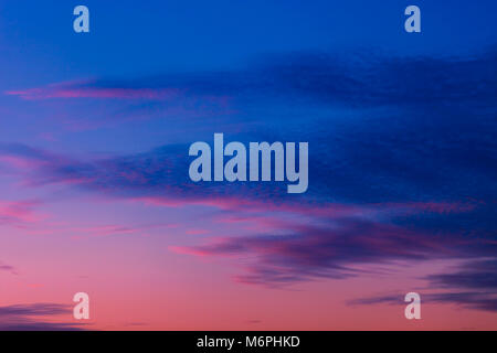 Pink and purple sunset sky with clouds painted in dark tones of blue Stock Photo