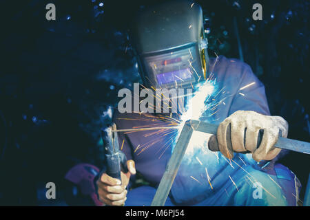 Welder wear protective mask welding metal structure with light sparkle Stock Photo