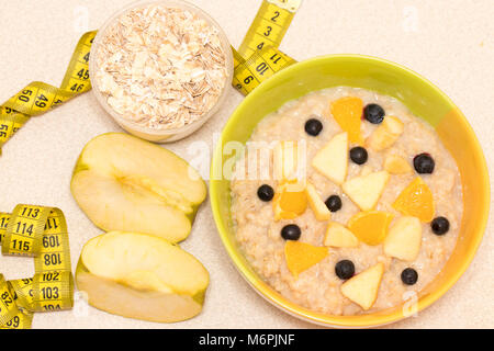 Morning healthy nutrition, diet frame with oatmeal porridge, fruits,and measuring tape. Perfect breakfast before workout Stock Photo