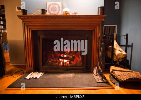 Burning cozy fireplace hearth with tools and gloves empty Stock Photo