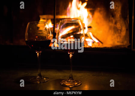 Pair of glasses with wine at fireplace nobody Stock Photo
