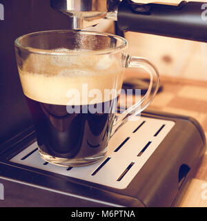 espresso machine pouring strong looking fresh coffee in a  glass cup. strong coffe. Stock Photo