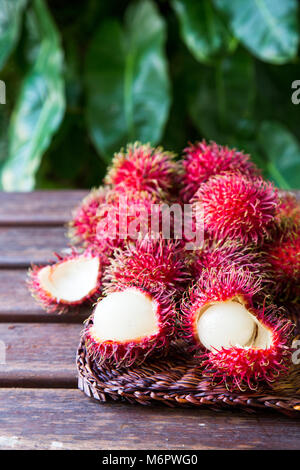 Fresh ripe rambutans on wooden background. Delicious rambutan sweet fruit. Stock Photo
