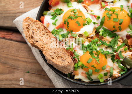 Shakshuka with eggs, tomato, and parsley in a iron pan. Shakshuka - traditional israeli tomato stew with eggs . Stock Photo