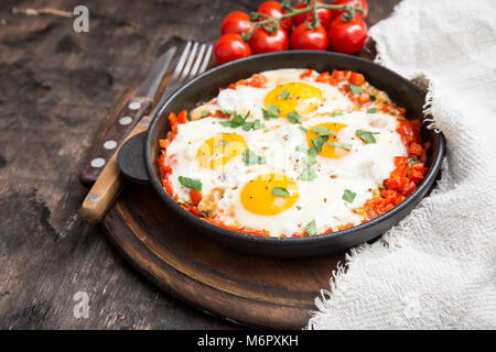 Tasty and Healthy Shakshuka in a Frying Pan. Fried eggs with tomatoes, bell pepper, vegetables and herbs. Middle eastern traditional dish Stock Photo