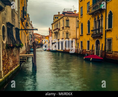 Small romantic canals and narrow aisles with peaks of home during sunset, Venice, Italy Stock Photo