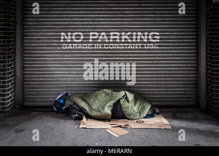 London, UK. 6th March, 2018. A rough sleeper during the day outside a garage in Southwark, South London. Credit: Guy Corbishley/Alamy Live News Stock Photo