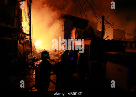 Quezon City, Philippines. 6th Mar, 2018. Firefighters extinguish fire at a slum in Quezon City, the Philippines, March 6, 2018. Credit: Rouelle Umali/Xinhua/Alamy Live News Stock Photo