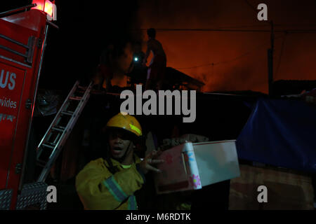 Quezon City, Philippines. 6th Mar, 2018. A firefighter help residents evacuate at a slum in Quezon City, the Philippines, March 6, 2018. Credit: Rouelle Umali/Xinhua/Alamy Live News Stock Photo
