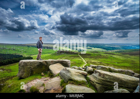 A rambler on Higger Tor in the Derbyshire Peak District with Carl Wark in the middle distance. Stock Photo