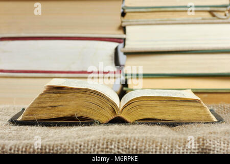 Open old book in a hard cover on a table with a jute background Stock Photo