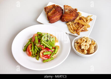 Thai traditional food, local food, long beans spicy salad (cow pea), Crispy pork skin and crisp tilapia fish fried on white background Stock Photo