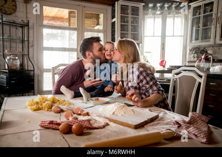 Happy family making pasta in the kitchen at home Stock Photo