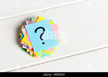multicolored question marks written reminders tickets on white wooden background. Stock Photo