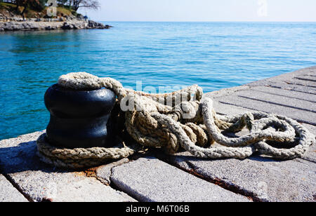 Mooring rope on the marine dock with coast and promenade in the background Stock Photo