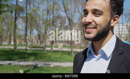 Trainee walking in park after work, smiling with dimples on face Stock Photo