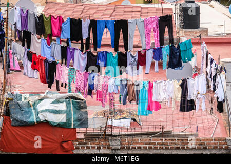 Many colorful clothes drying outside on ropes on a rooftop in Guanajuato, Mexico Stock Photo