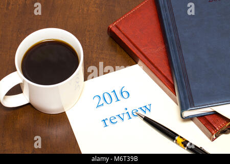 The 2016 review the text on the sheet of paper next to a Cup of coffee, pen, business diary on wooden table Stock Photo