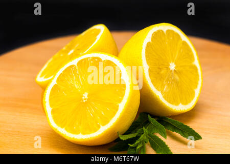 Half of lemon on a wooden board. Lemons  on a wooden background. Lemons. Fruits. Lemon halves. Mint. Healthy food concept. Copyspace. Stock Photo