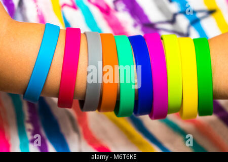 Rubber bands on hand. Girls hand with bracelets made of rubber bands. Rainbow loom colored rubber bands. Stock Photo