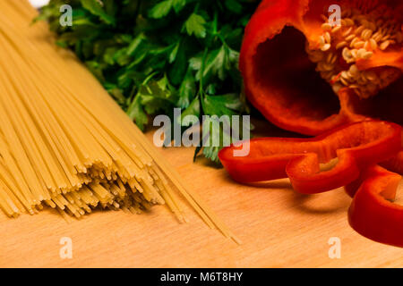 Fresh ingredients for cooking: pasta and  peppers and parsley on wooden background table. Stock Photo
