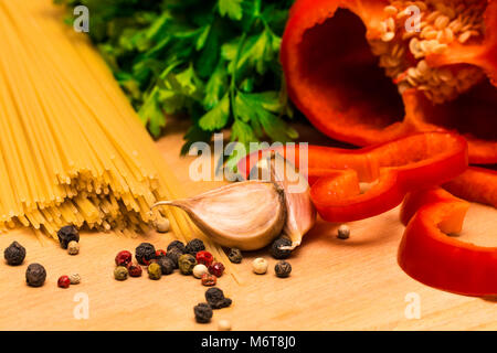 Fresh ingredients for cooking: pasta and  peppers and parsley on wooden background table. Stock Photo