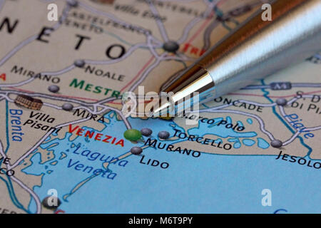 Macro image of a ballpoint pen pointing at Venice on the map of Italy. Shallow depth of field. Stock Photo