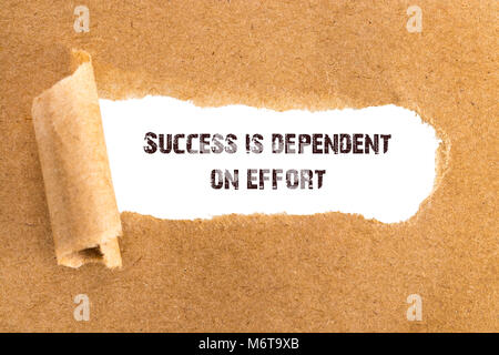 The text Success is dependent on effort appearing behind torn brown paper. Stock Photo