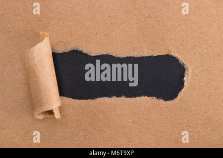 holes in brown paper with torn sides over paper background with space for text. Stock Photo
