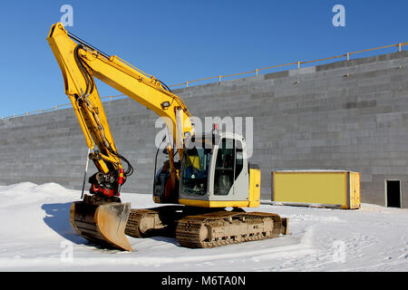 Yellow excavator on a construction site in winter. Stock Photo