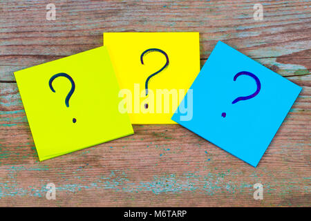 questions, decision making or uncertainty concept - a pile of colorful sticky notes with question marks on wooden background. Stock Photo