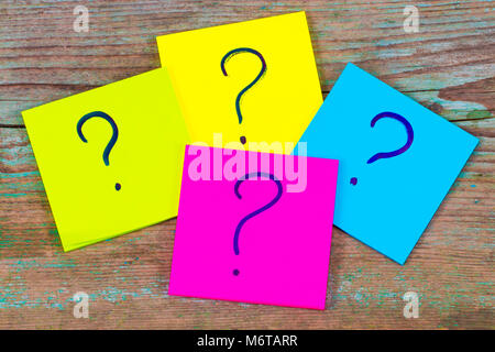questions, decision making or uncertainty concept - a pile of colorful sticky notes with question marks on wooden background. Stock Photo