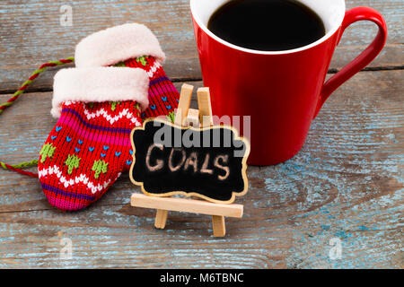 Goals - handwriting message on blackboard with a Cup of coffee and mittens, New Year resolutions concept. Stock Photo