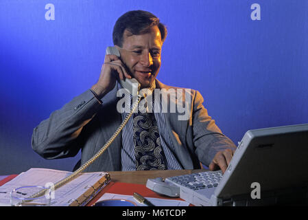 1994 HISTORICAL CAUCASIAN BUSINESS MAN AT DESK IN OFFICE LOOKING AT LAPTOP COMPUTER (©TOSHIBA 1994) Stock Photo