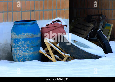 The old blue plastic barrel is thrown into the snow on an abandoned and destroyed factory amidst chaos. Destruction and vandalism. Ukraine. Stock Photo