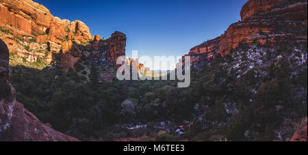 Stunning panorama of Fay Canyon from above the treetops with patches of snow on the ground and majestic views of Bell Rock and Courthouse Butte in the Stock Photo