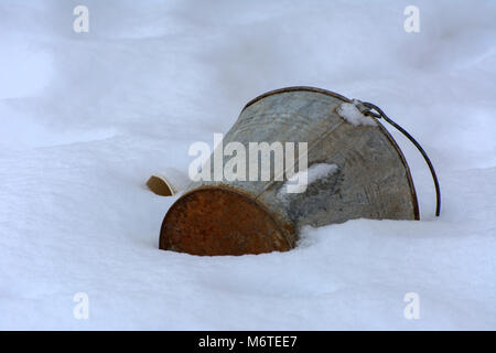 An old white plastic bucket is thrown in winter on an abandoned and destroyed factory against the background of snow. Destruction and vandalism. Ukrai Stock Photo