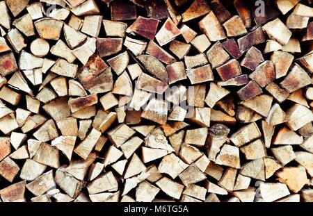 Stack of firewood. Renewable resource of a energy. Environmental concept.Close-up of a stack of firewood. Pile of stacked firewood in rural garden. Stock Photo